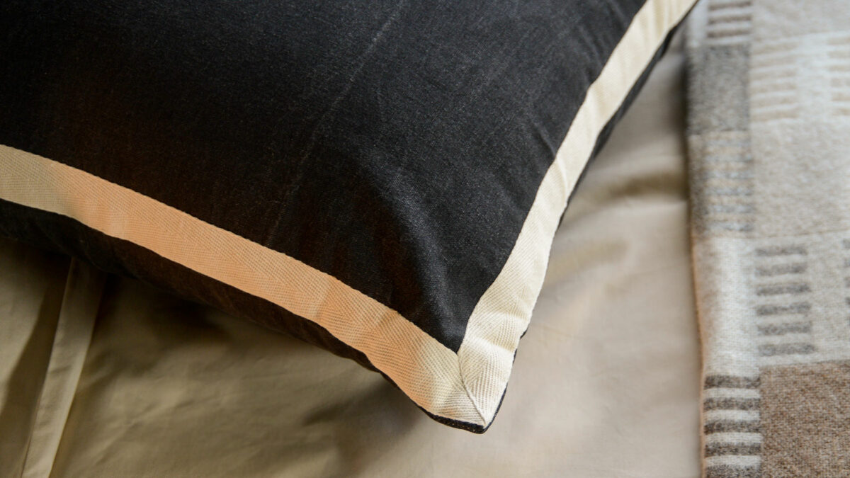 black cotton cushions with ivory coloured edges shown close up