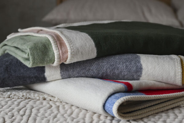 Stack of three neatly folded throw with abstract designs.