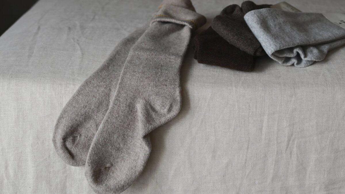 long cozy socks with a hint of cashmere on bed. 3 pairs folded and one pair laid out flat.