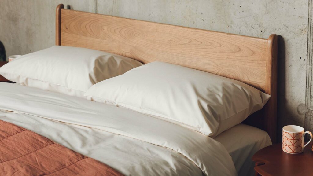 cream-coloured classic organic cotton bedding shown on a cherry wood low Carnaby bed