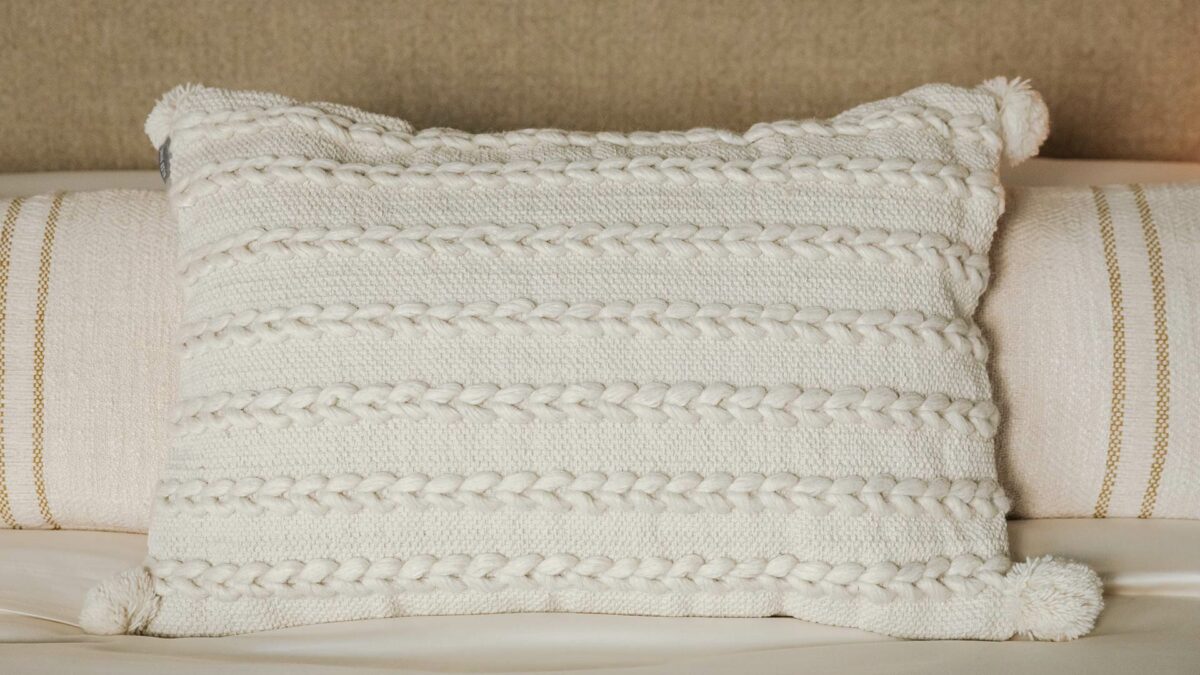cream cushion with woven texture and pom pom detail