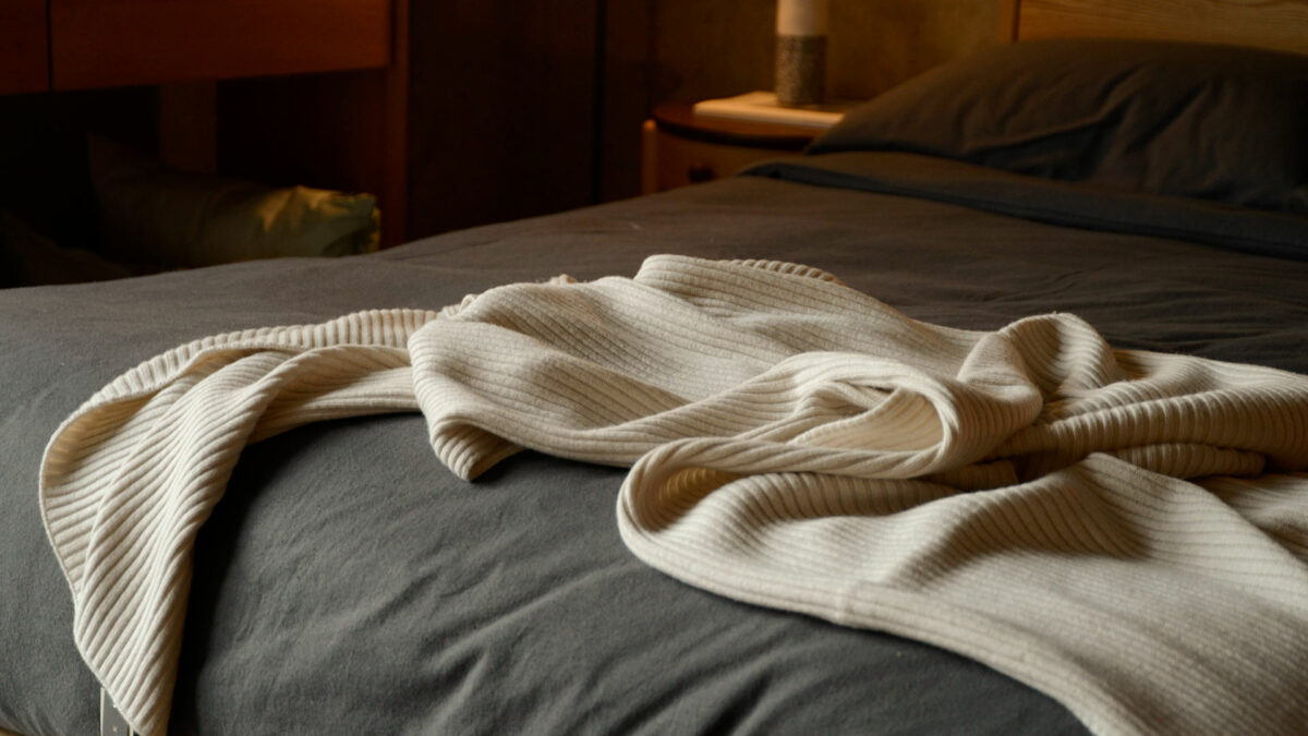 luxury knitted bed runner in cream shown draped on a bed