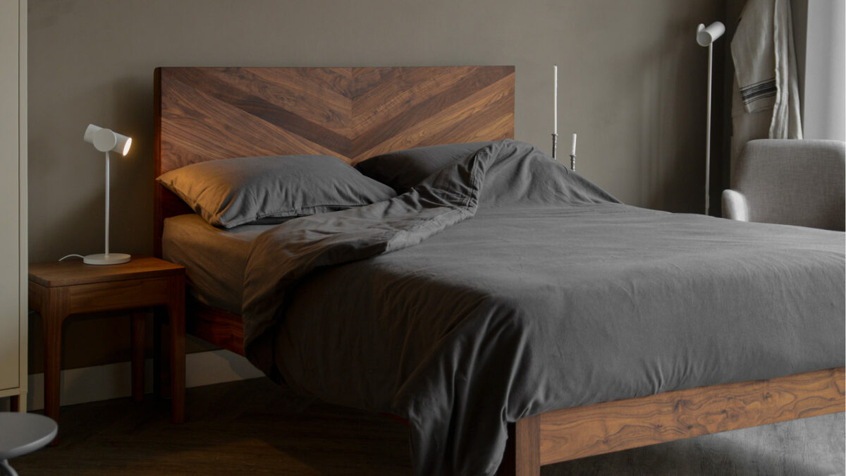 striking oiled walnut Hathersage bed handmade in uk shown with dark grey bedding