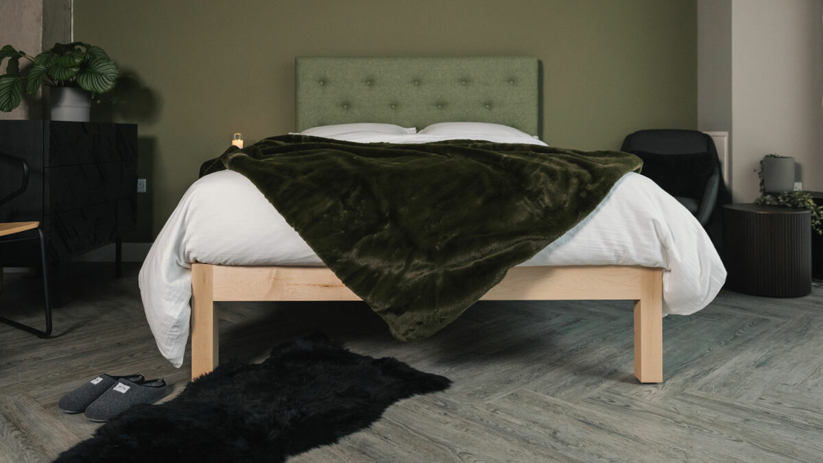 dark green faux fur throw shown draped on a kingsize bed