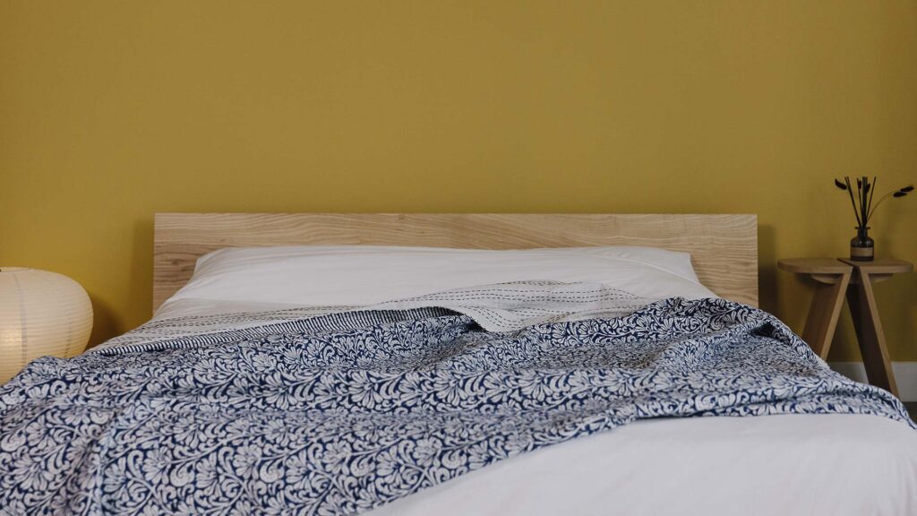 blue floral bedspread draped over white bedding on an Oregon bed frame.