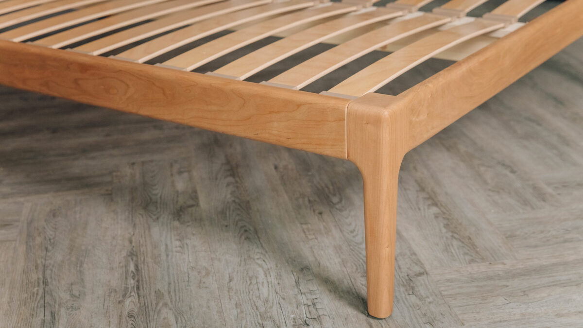 a close up of the leg at the foot end of our cherry wood Hoxton bed shown without mattress