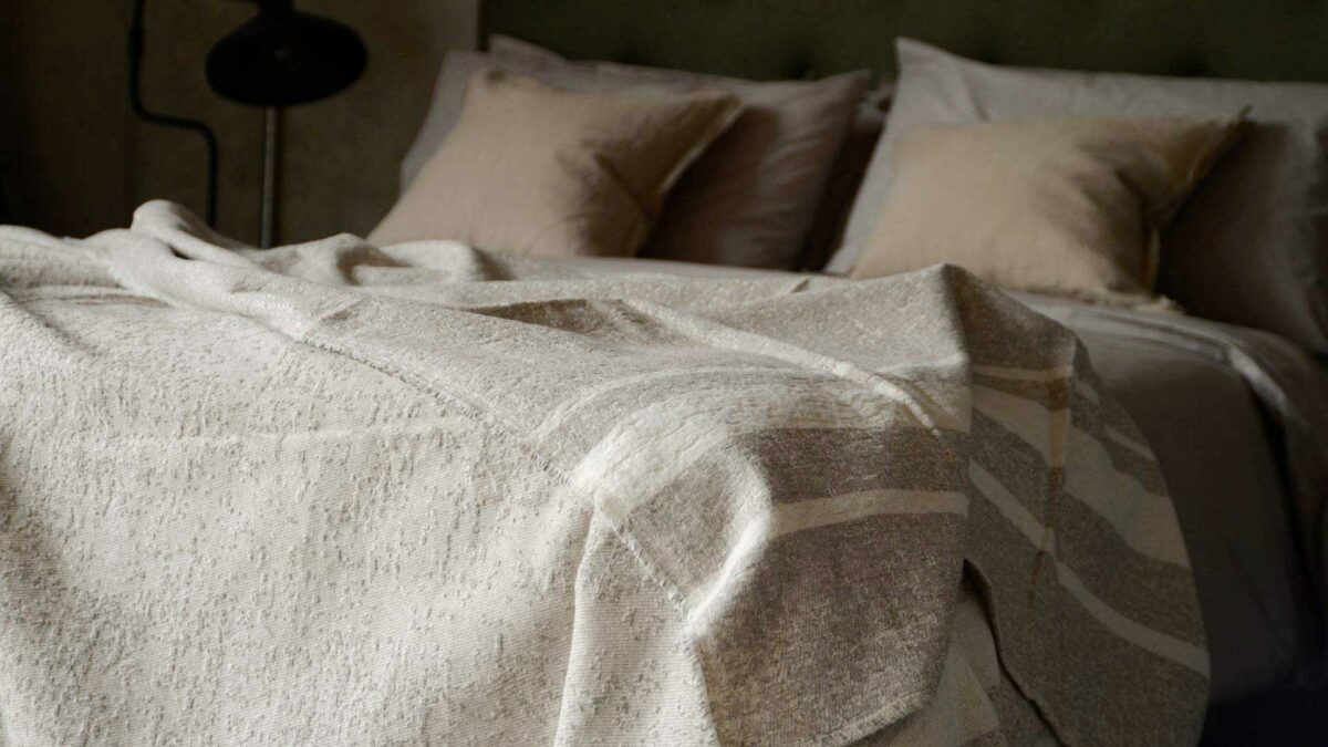 cotton rich textured bedspread in ecru and ivory shown draped on a bed