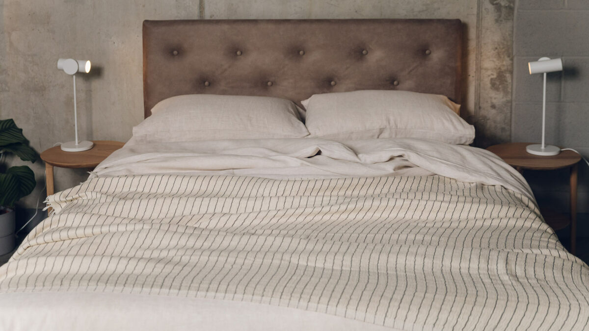 ecru linen bedding shown with a lightweight striped cotton throw