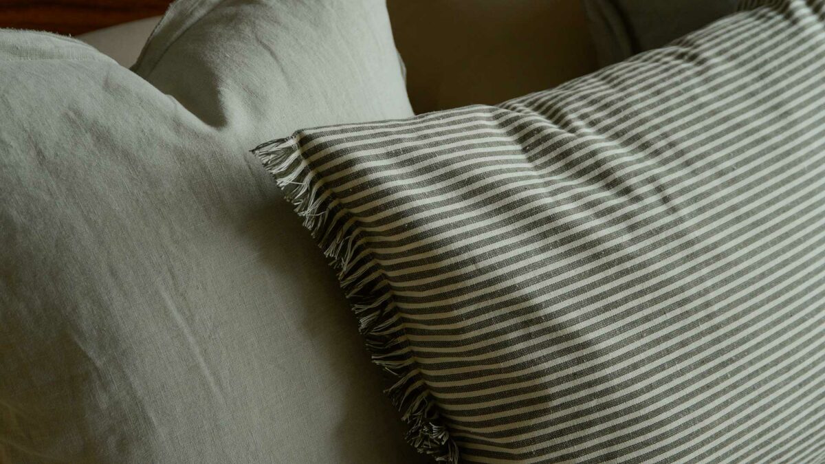 olive green and white striped cotton cushions with frayed edging shown close to