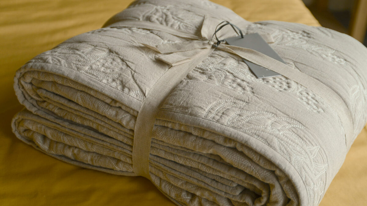 Reversible stitched and quilted bedspread ivory one side beige the other shown folded