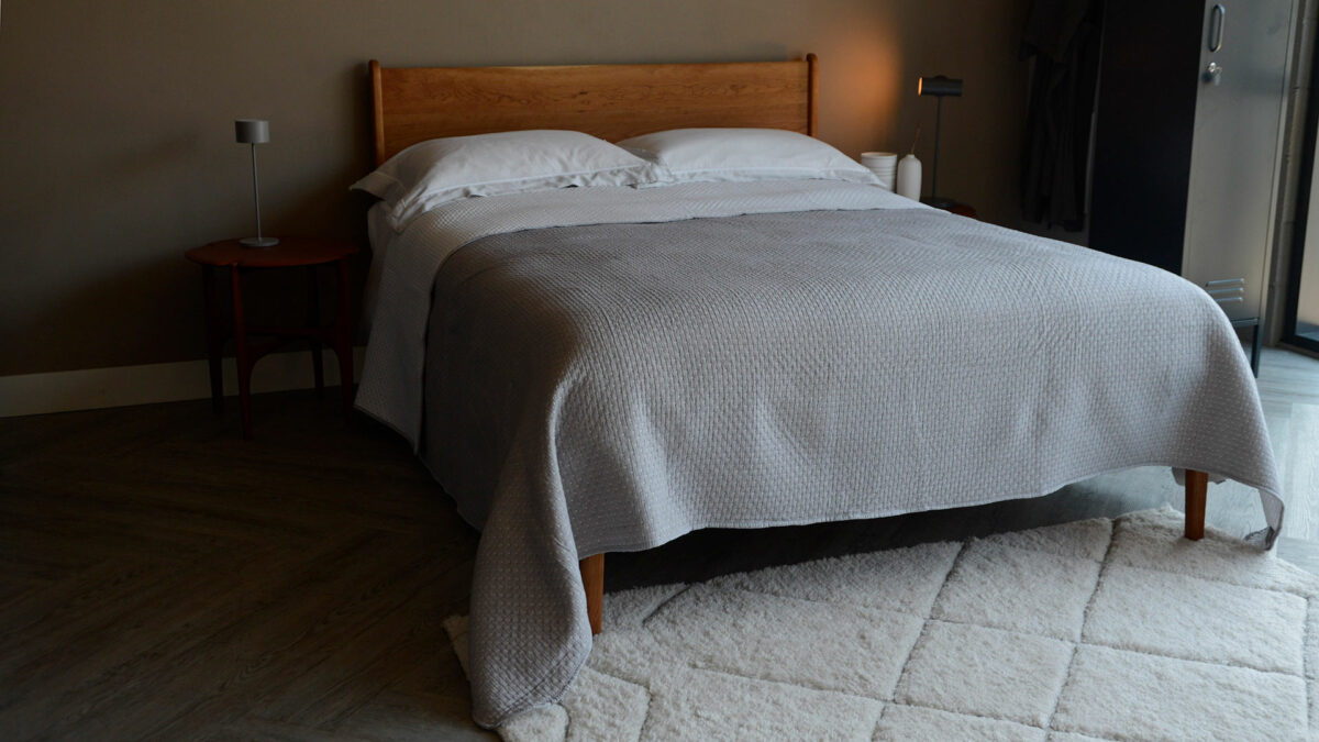 reversible stitched polka dot quilted bedspread in grey and white shown on a kingsize bed