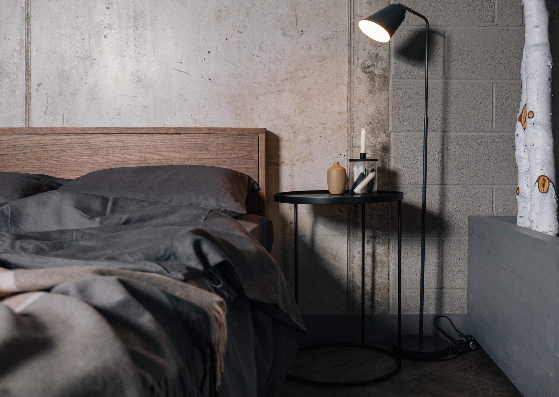 Black circular top side table used as a Bedside table with our Leith wooden bed