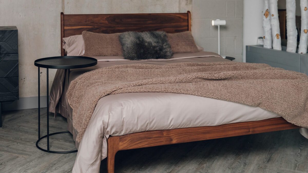 Camden mid-century style bed in oiled walnut wood shown with a circular top overhanging side table by Ethnicraft