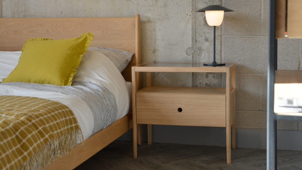 Spindle is an Oak bedside table with storage drawer and open shelf. It is shown with our mid-century style Oak Carnaby bed.