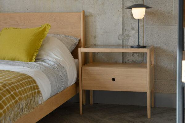 Spindle is an Oak bedside table with storage drawer and open shelf. It is shown with our mid-century style Oak Carnaby bed.