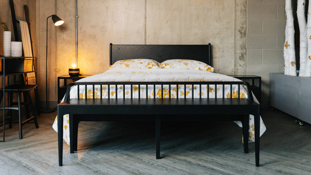 slender spindle bench in black oak shown at the end of a kingsize Camden bed