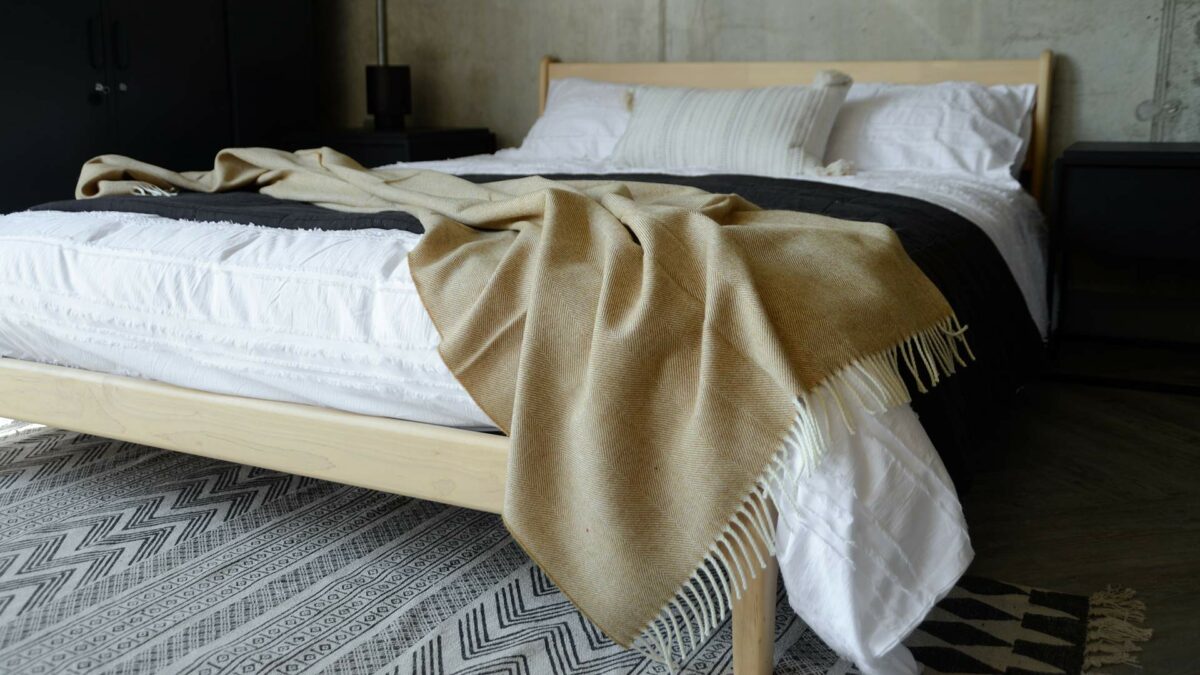 large herringbone weave merino wool throw in caramel shown on a kingsize bed