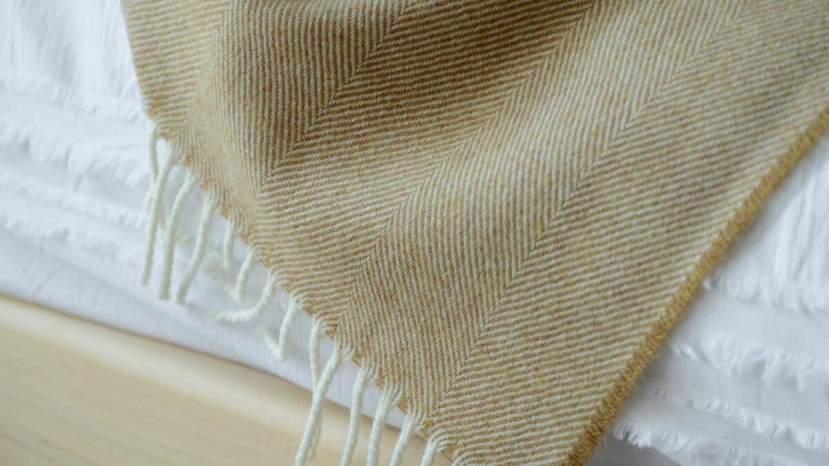 Large herringbone weave merino wool throw in caramel and ivory a close up view