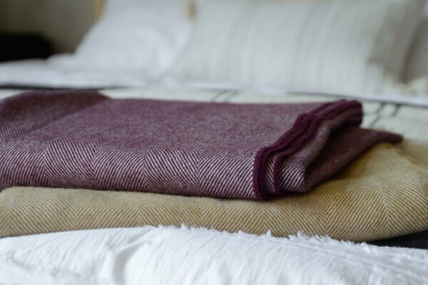 large herringbone weave merino wool throws in berry and caramel colour options, a close up view