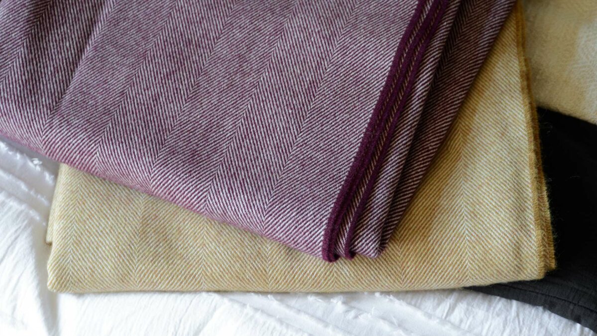 large herringbone weave merino wool throws in berry and caramel colour options, a close up view