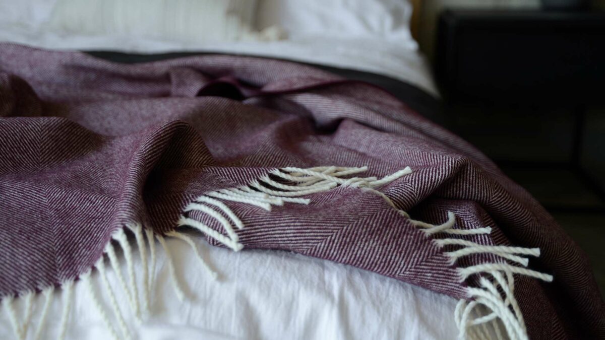 large herringbone weave merino wool throw in berry and ivory, a close up view