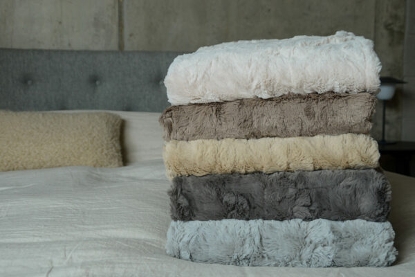 softest faux fur throws in a range of neutral colours shown in a stack