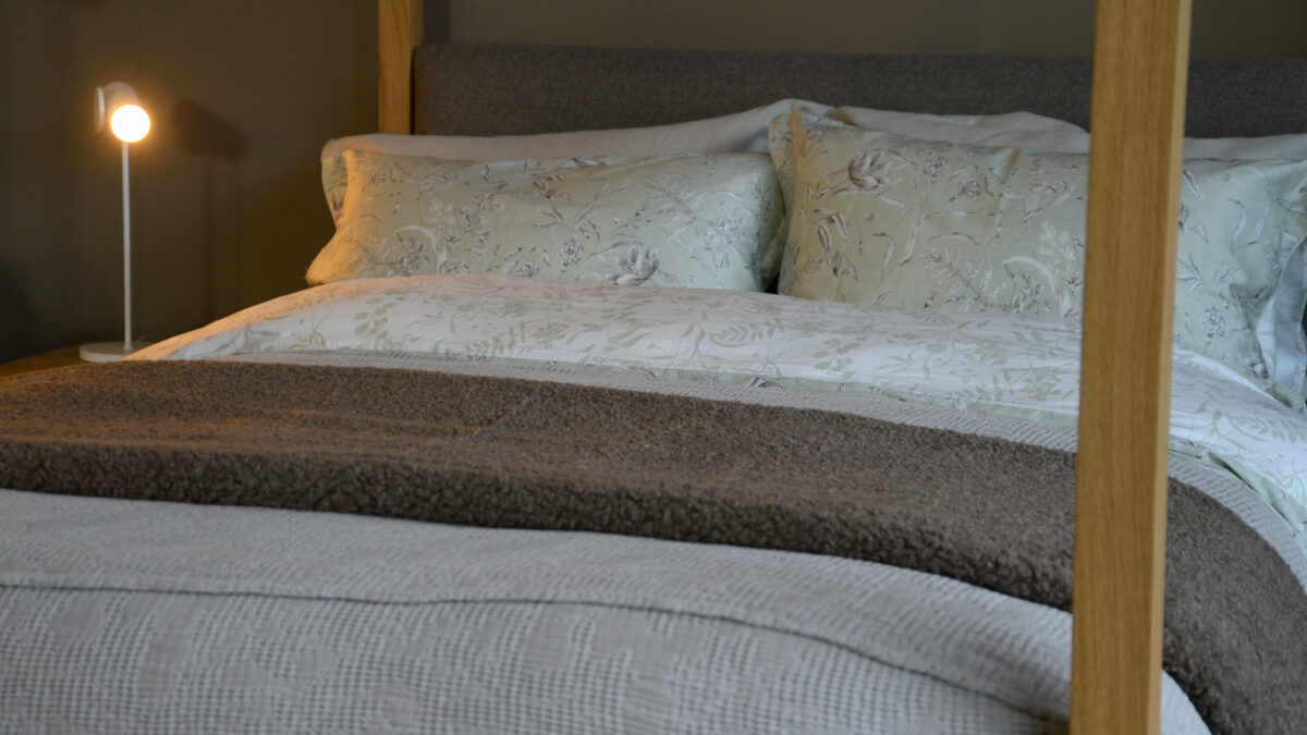 soft sheepskin effect fleecy throw in mushroom brown shown on a bed