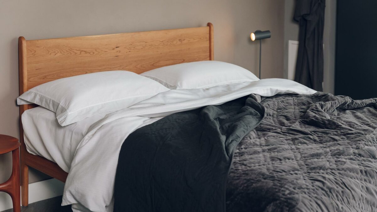 luxury quilted bedspread in charcoal grey velvet shown draped on a Kingsize cherry wood Camden bed