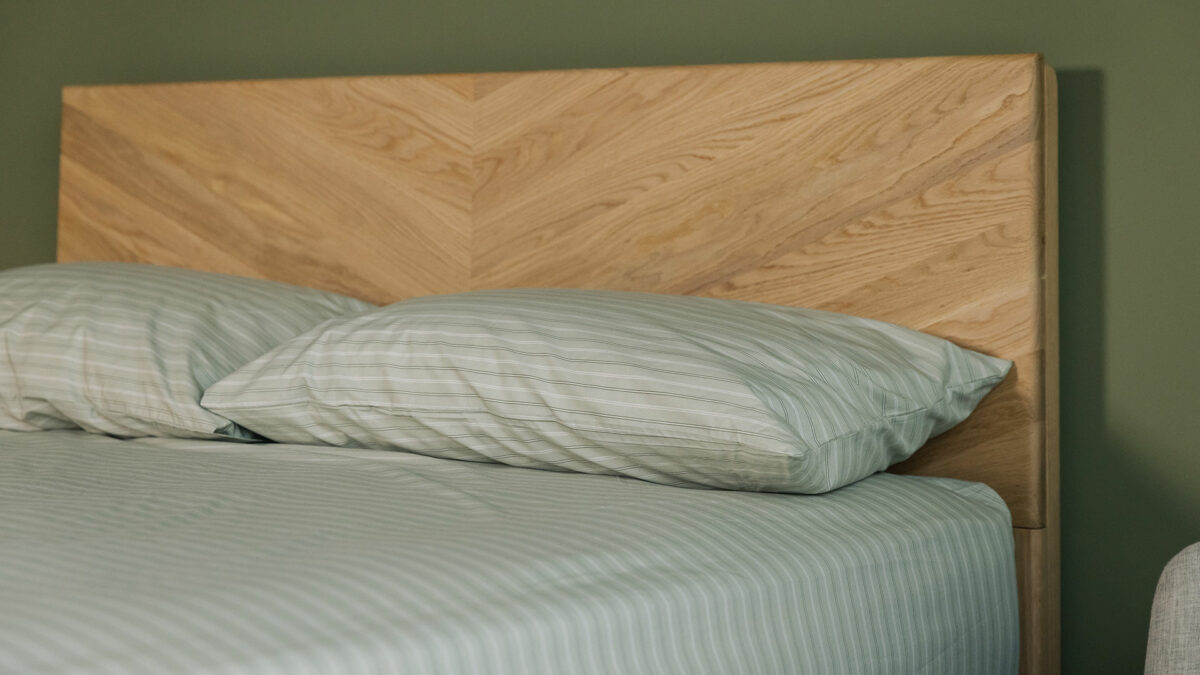 sage green striped fitted sheet and pillowcase set shown on an oak bed