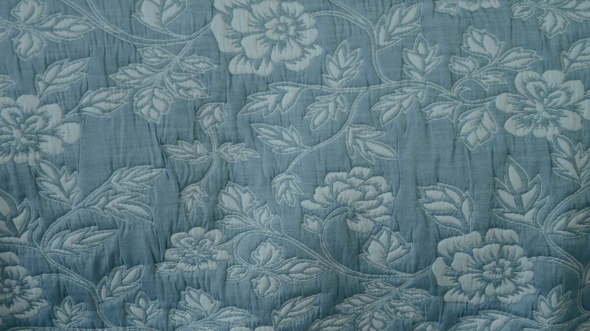 Wedgwood blue and ivory floral patterned reversible quilted bedspread a close up of the stitched design