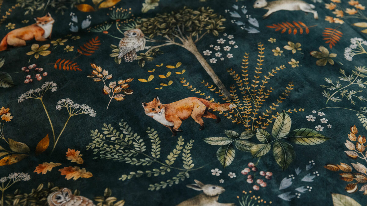 Dark green bedding with a nature print of foxes, plants, and owls a close up view