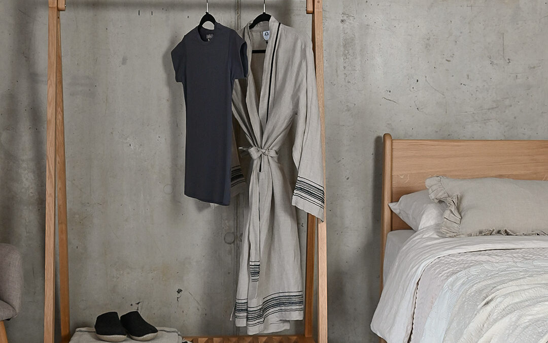 Portrait image showing the Solid Oak Freestanding Clothes Rail with a t-shirt and cotton robe hanging from it.