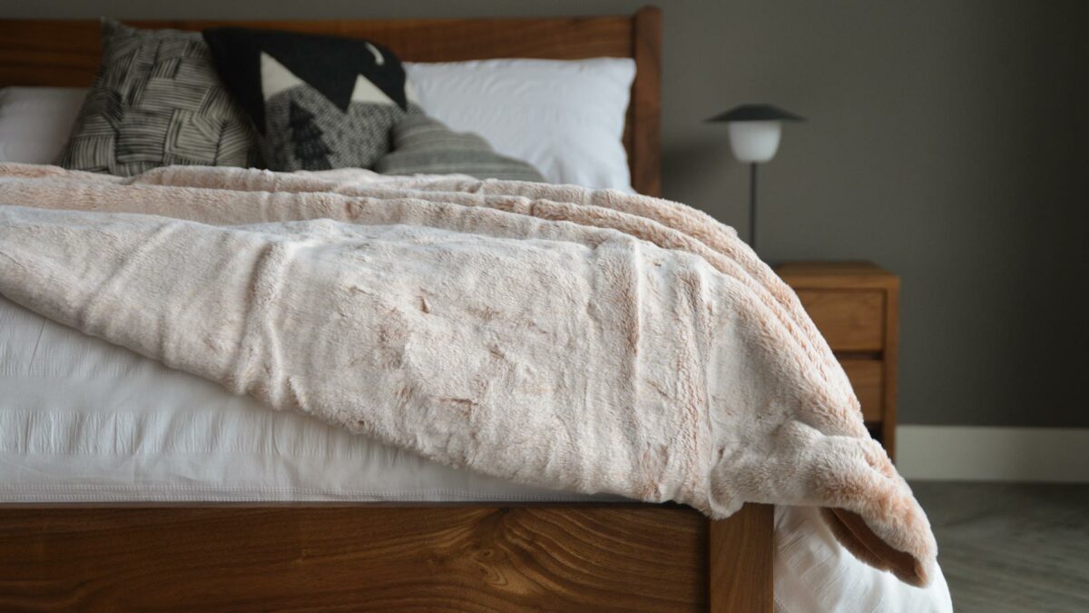 Frosted pink coloured faux fur throw on our walnut Cochin bed