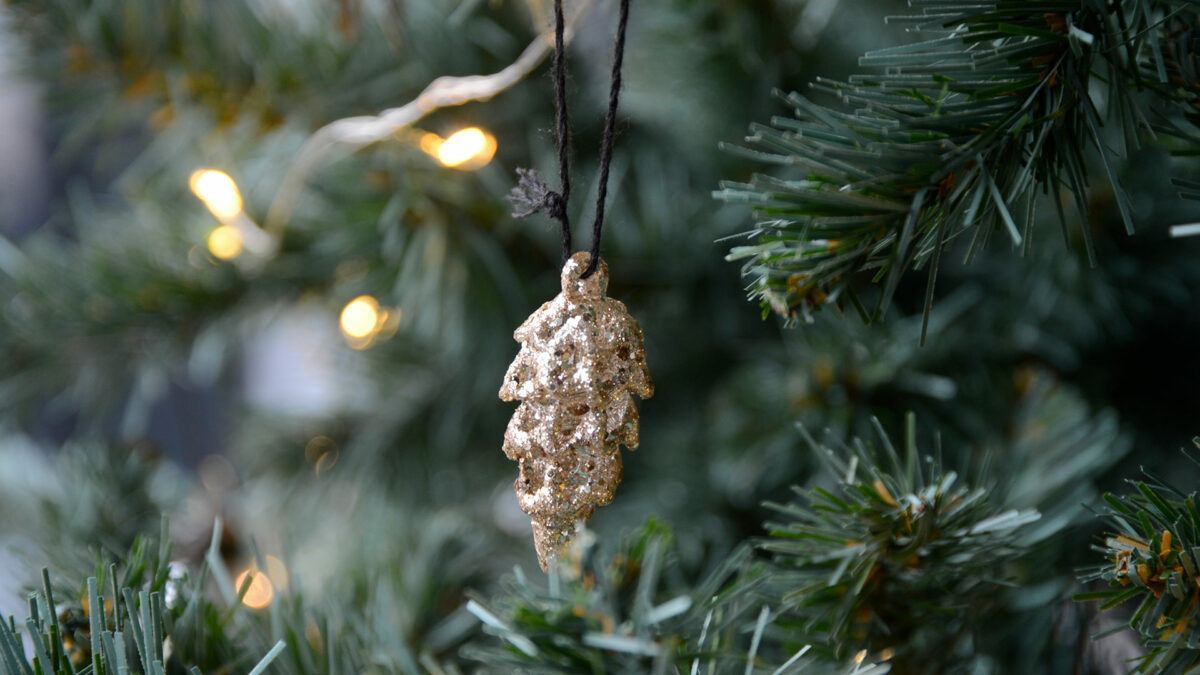 glittery gold Pine cone Christmas decoration shown on a tree