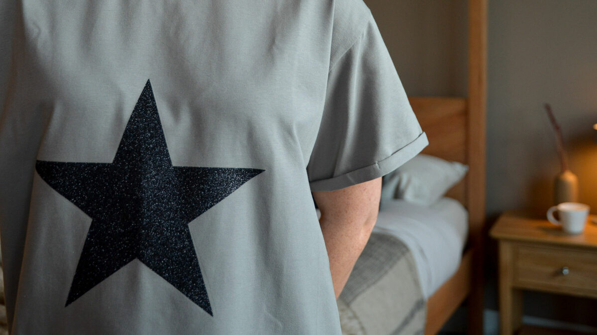 grey T shirt with black glitter star motif shown close up