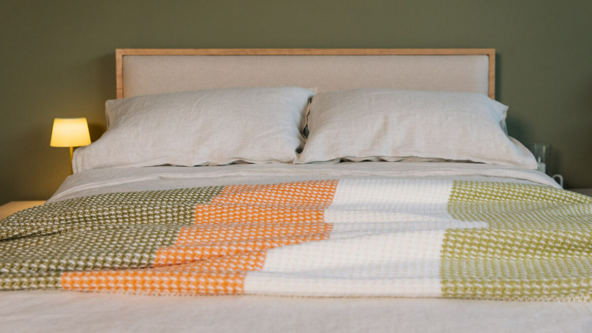 waffle knitted colour block throw in white green and orange shown on a kingsize bed