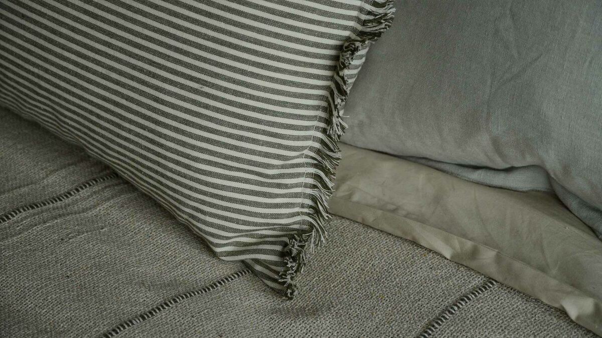 olive green and white striped cotton cushions with tassel edging shown close to