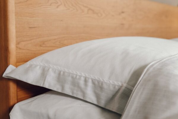 pale grey and ivory thin stripe duvet cover set shown in close up on a cherry wood Camden bed