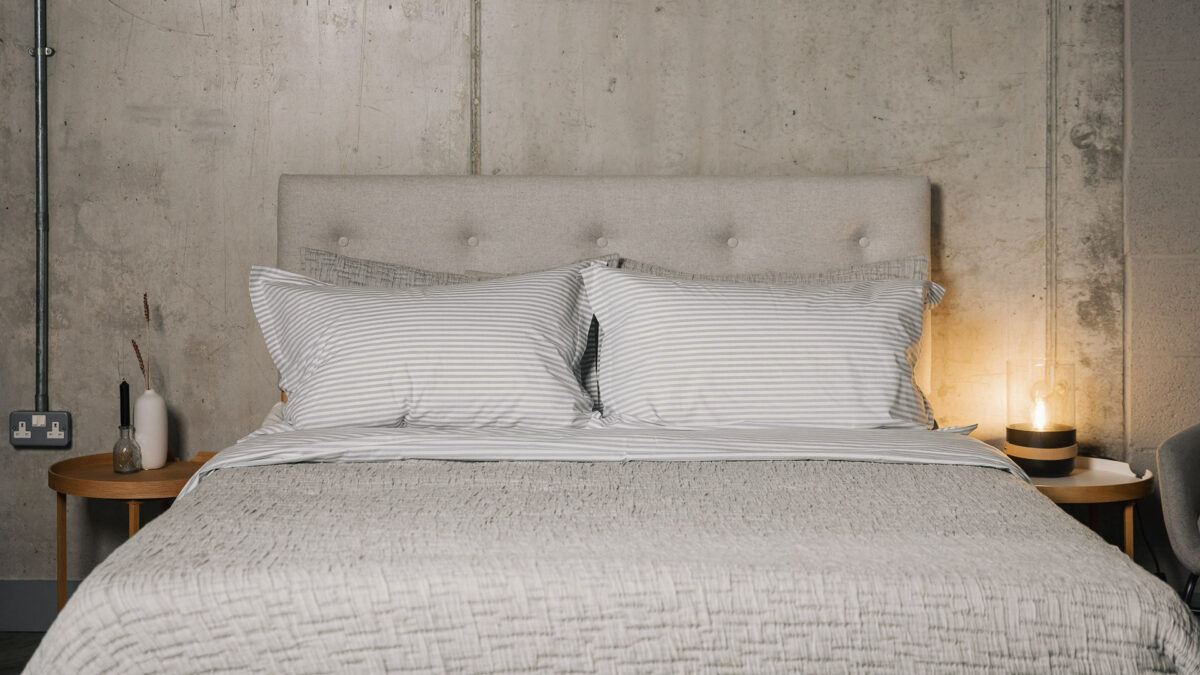 grey textured bedspread with matching pillowcases shown with grey striped bedding