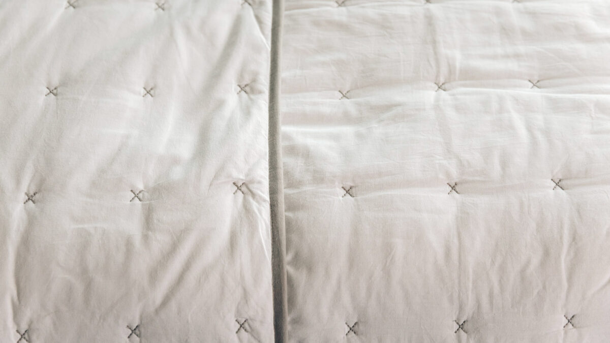 white cotton quilted bedspread with grey cross stitch details