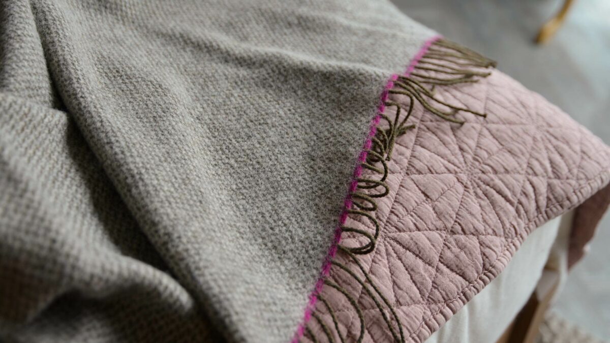 woven pure wool throw in greys with bright pink contrast edge