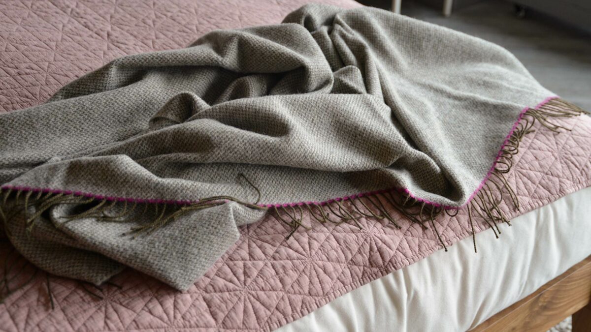 woven pure wool throw in greys with bright pink contrast edge