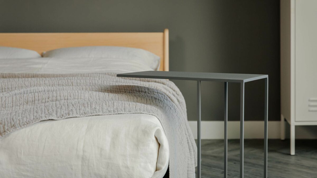 grey metal side table with neutral bedding