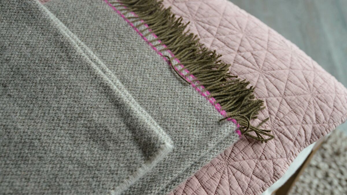 woven pure wool throw in greys with bright pink contrast edge