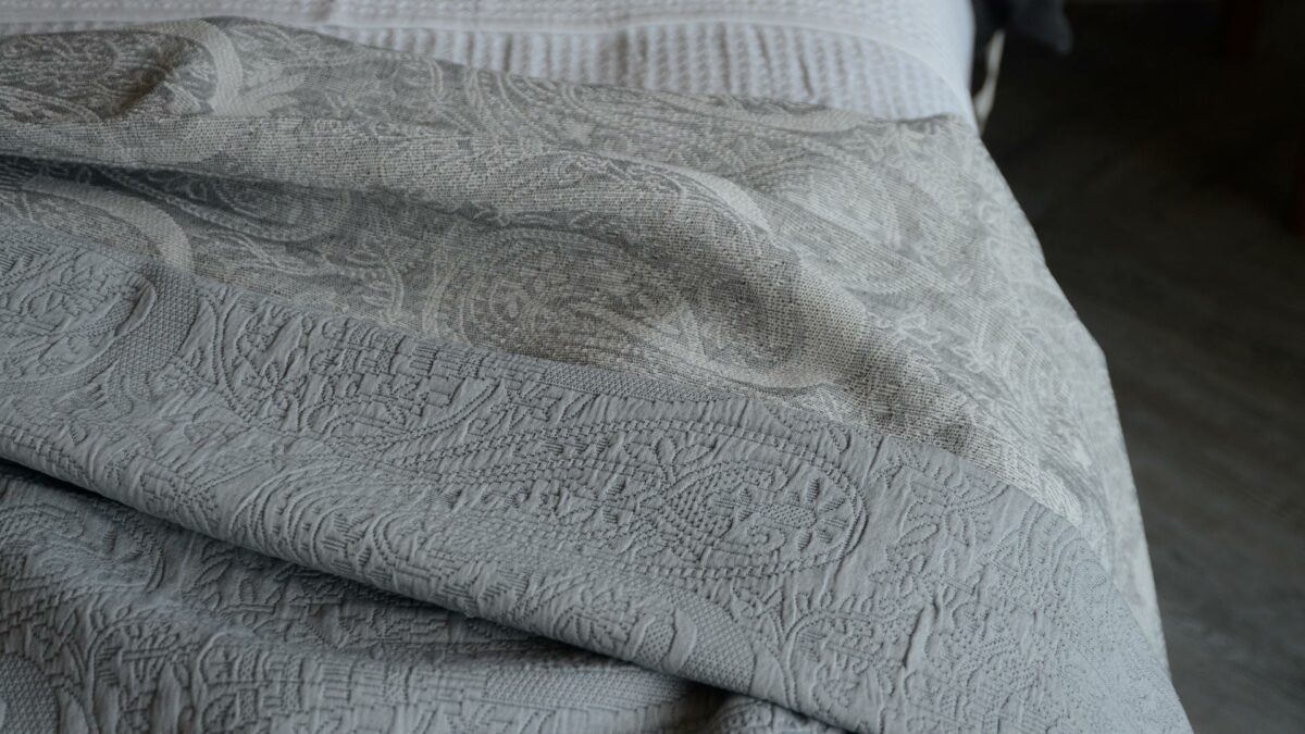 grey paisley look paterned bedspread detail with reverse