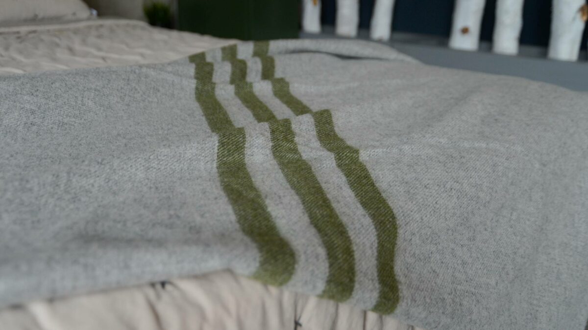 grey marl woollen throw with green stripes shown close up