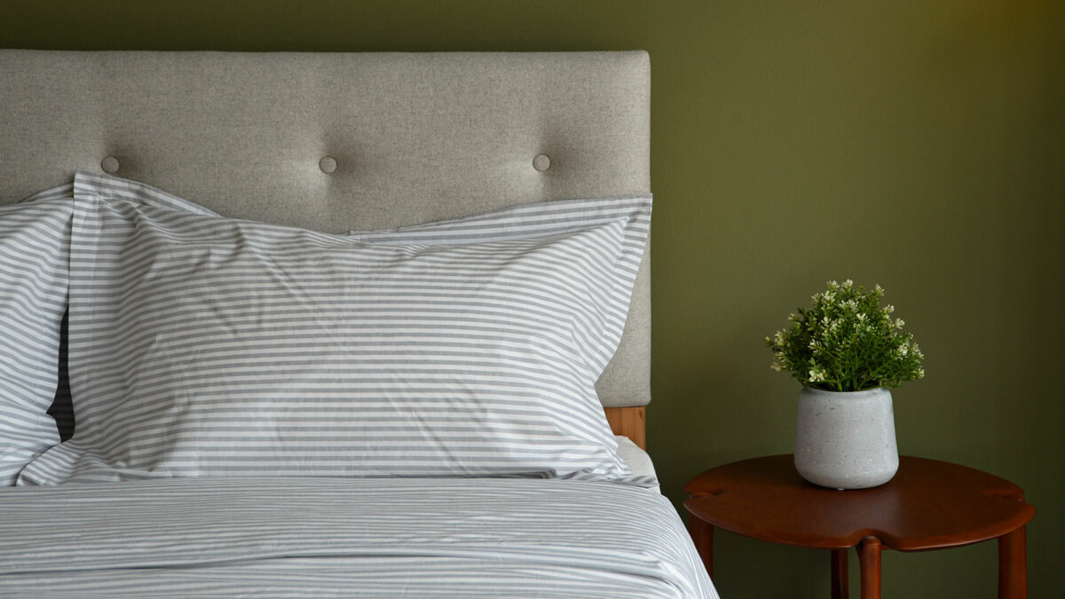 grey stripe cotton bedding pillow detail with pi table and plant