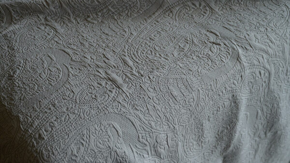 pale grey embroidered pattern bedspread with a paisley design