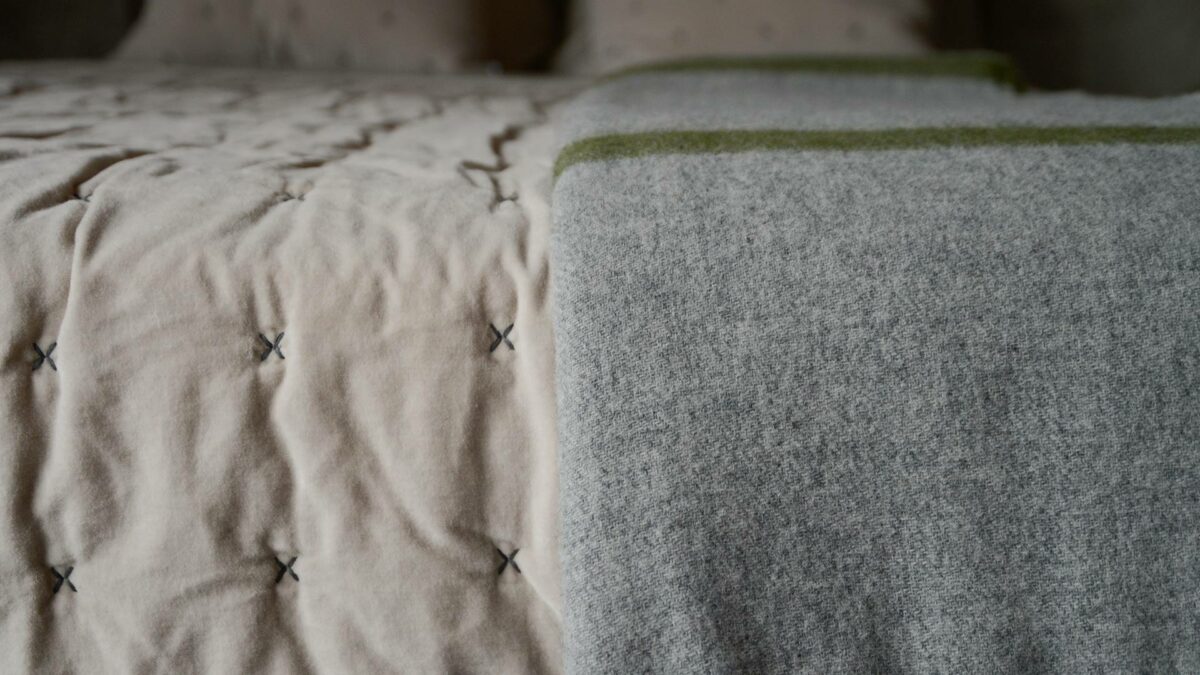 grey marl woollen throw with green stripes shown close up