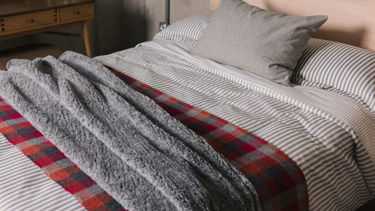 grey white striped bedding with red check throw and grey fleece
